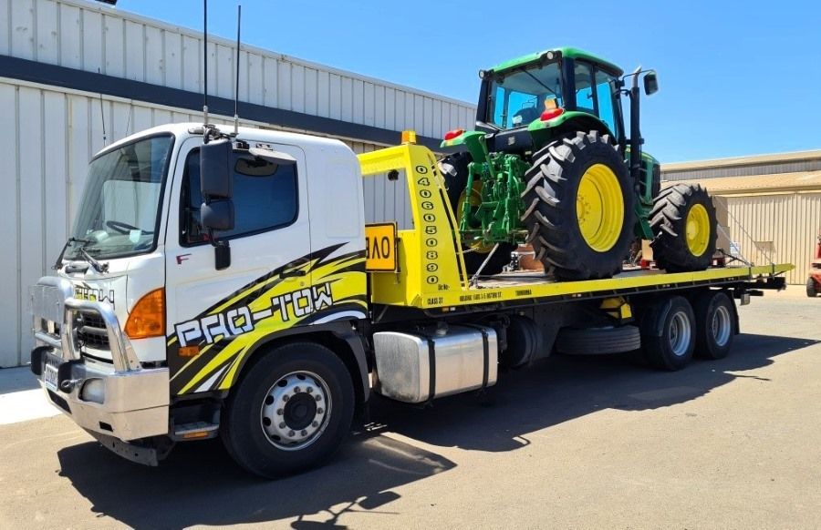 A Tow Truck is Carrying a Green John Deere Tractor — Pro-Tow Toowoomba in Wilsonton, QLD