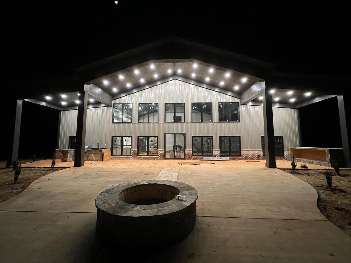 A large building with a fire pit in front of it at night.