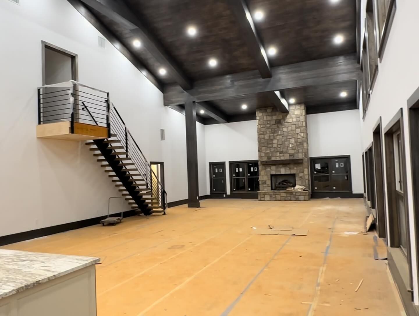 A large empty room with a fireplace and stairs.