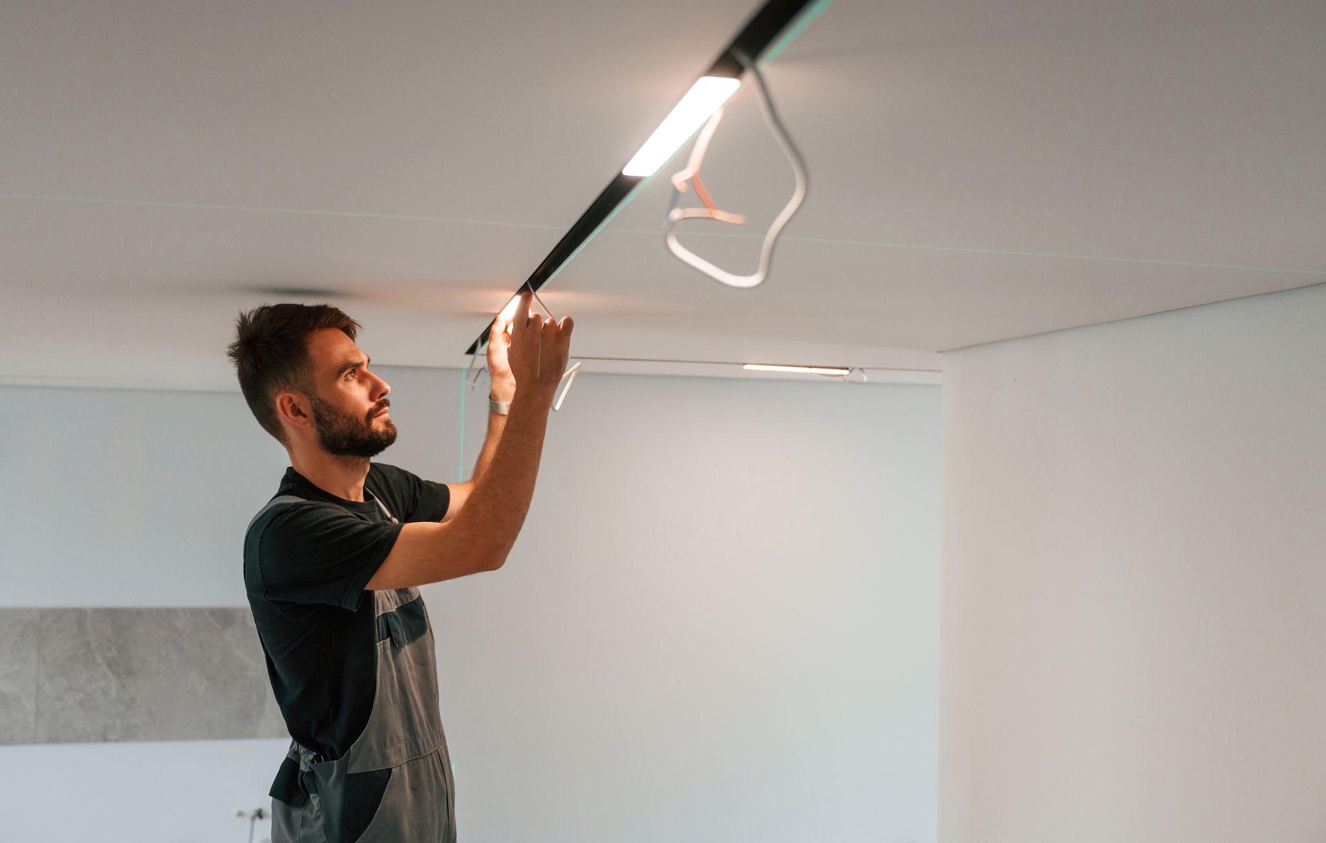 A man is installing a light on the ceiling of a room.