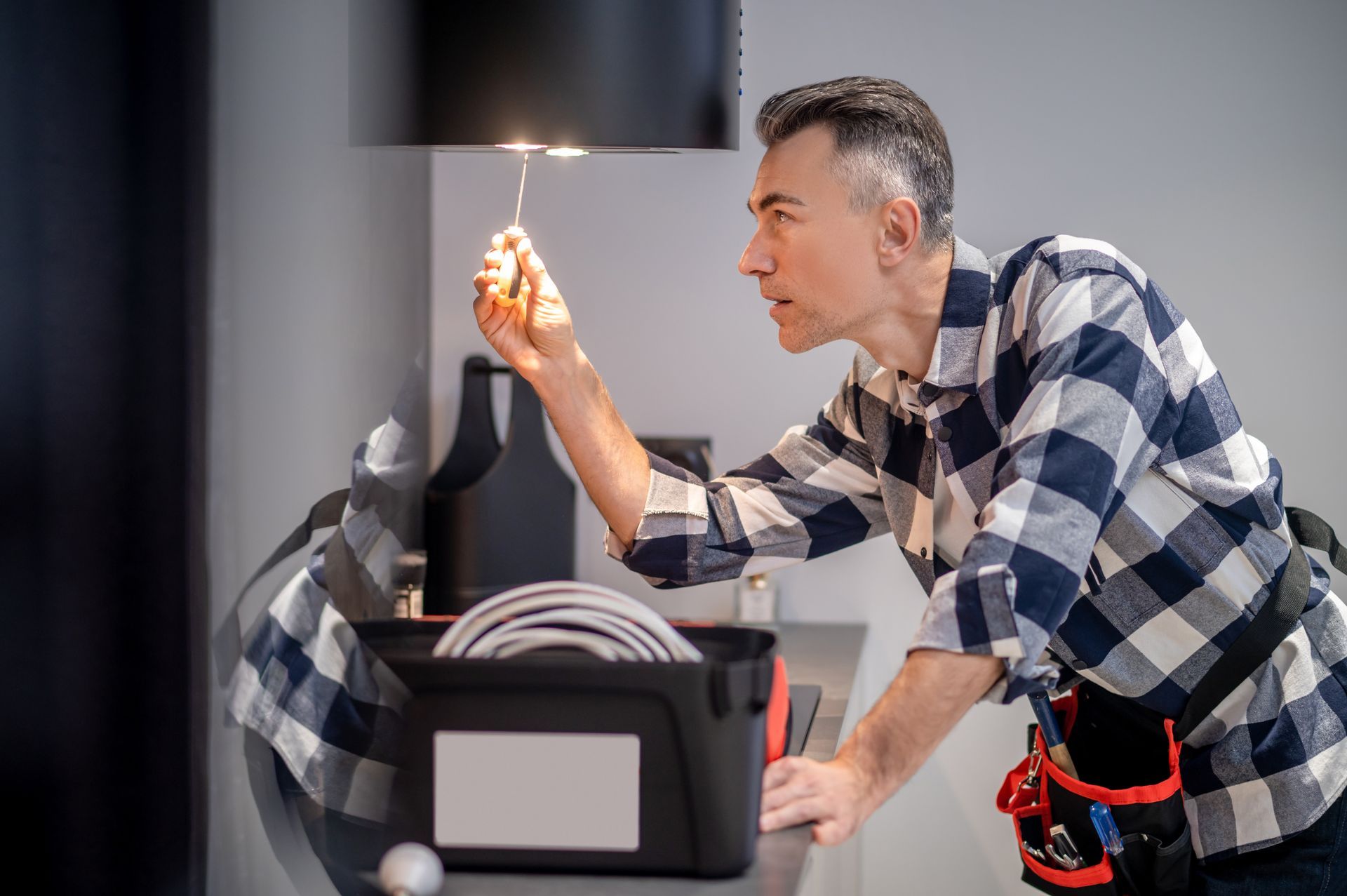 A man is fixing a lamp with a screwdriver.