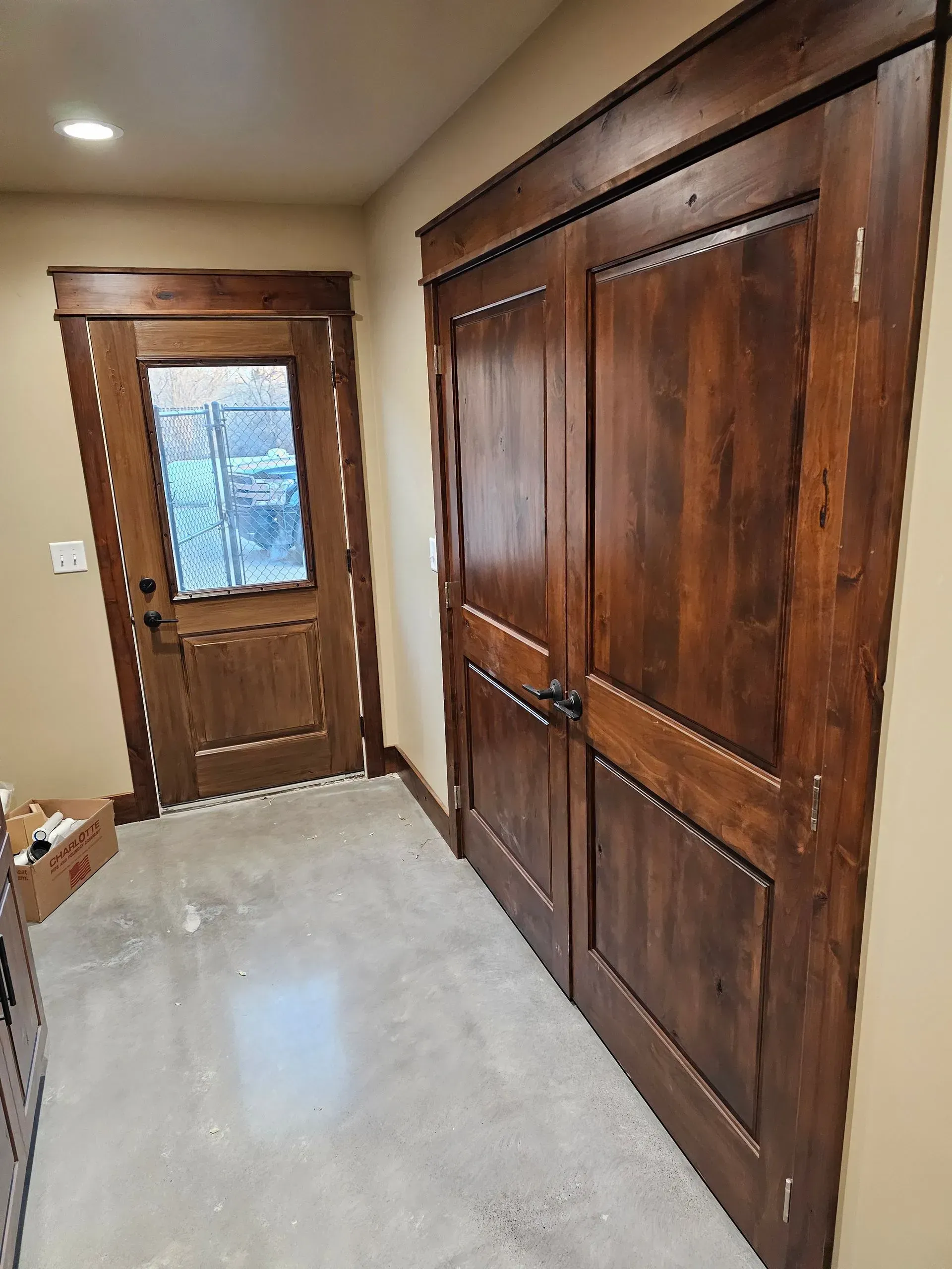 A hallway with two wooden doors and a concrete floor.