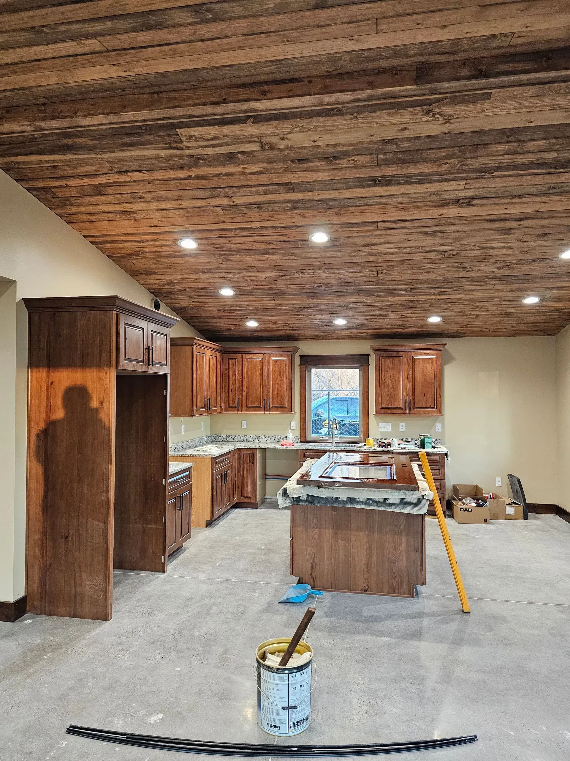 A kitchen under construction with wooden cabinets and a wooden ceiling.
