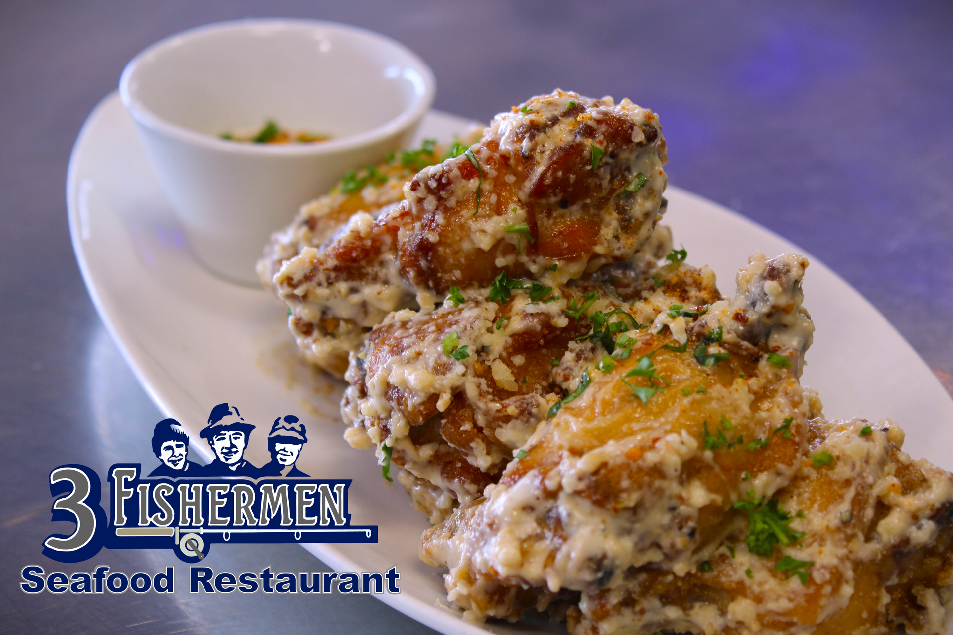 A white plate topped with fried chicken wings and a small bowl of dipping sauce.