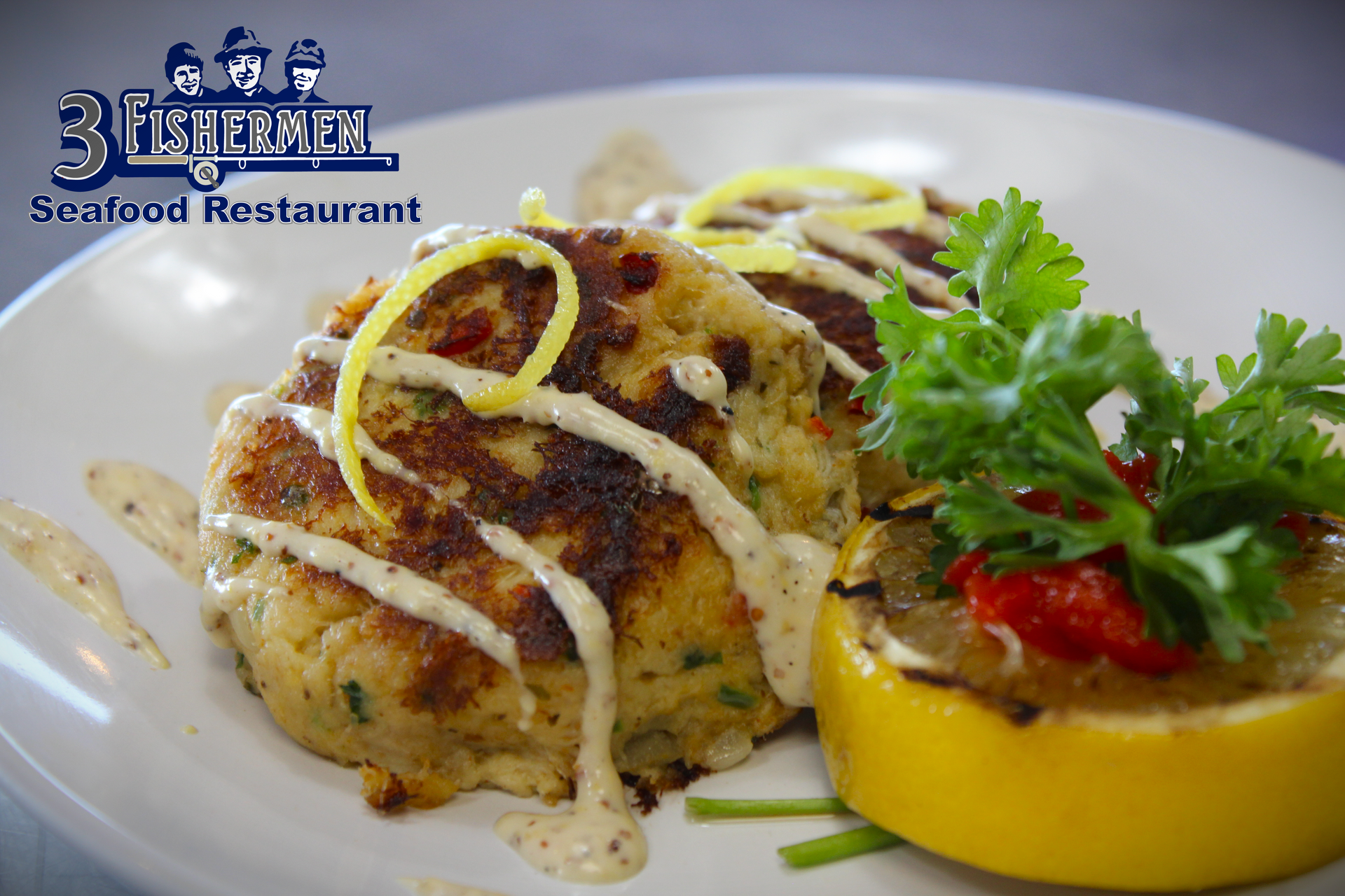 A white plate topped with crab cakes and a slice of lemon
