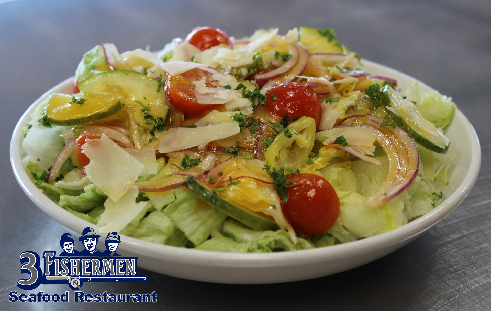 A salad with tomatoes , cucumbers , onions and cheese is in a white bowl.