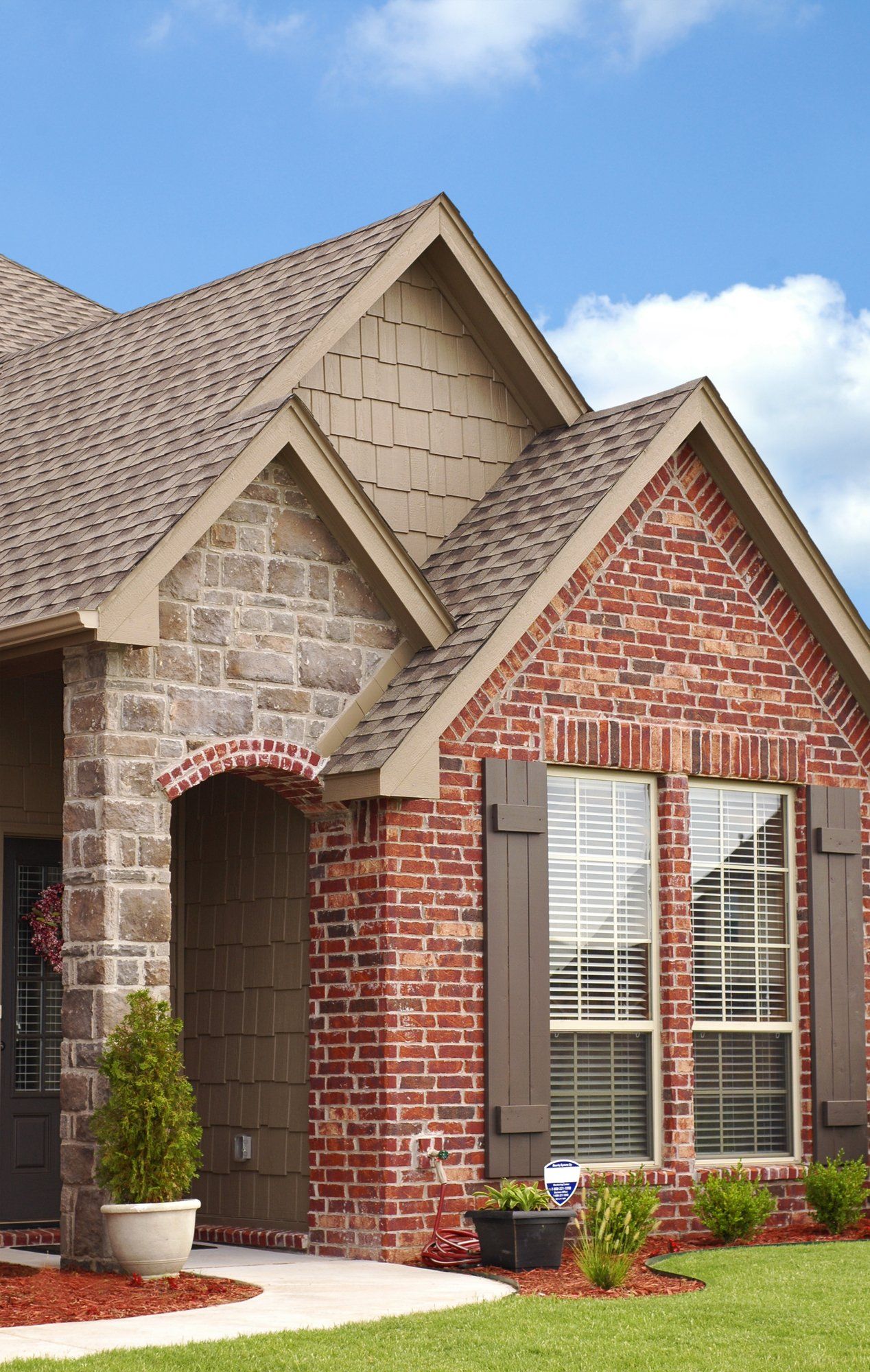 A brick and stone house with a roof and shutters