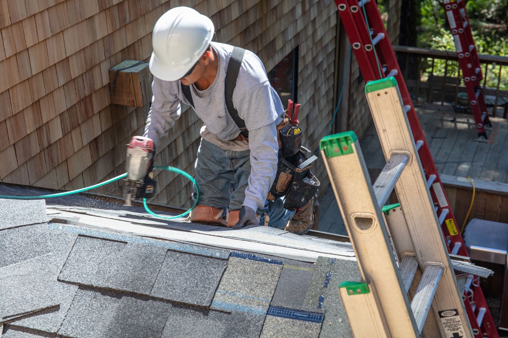 Installing a new roof with a nail gun and shingles.