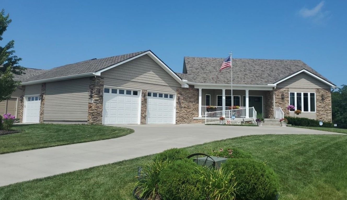 A large house with three garage doors and an american flag in front of it