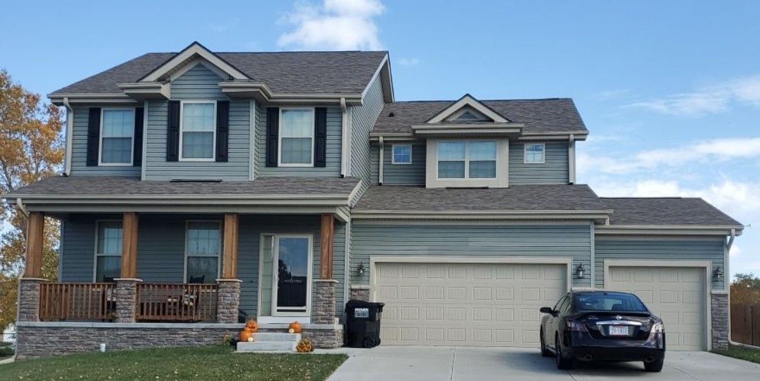 A car is parked in front of a large house.