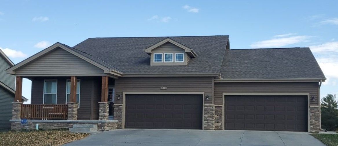 A large house with three garage doors and a porch.