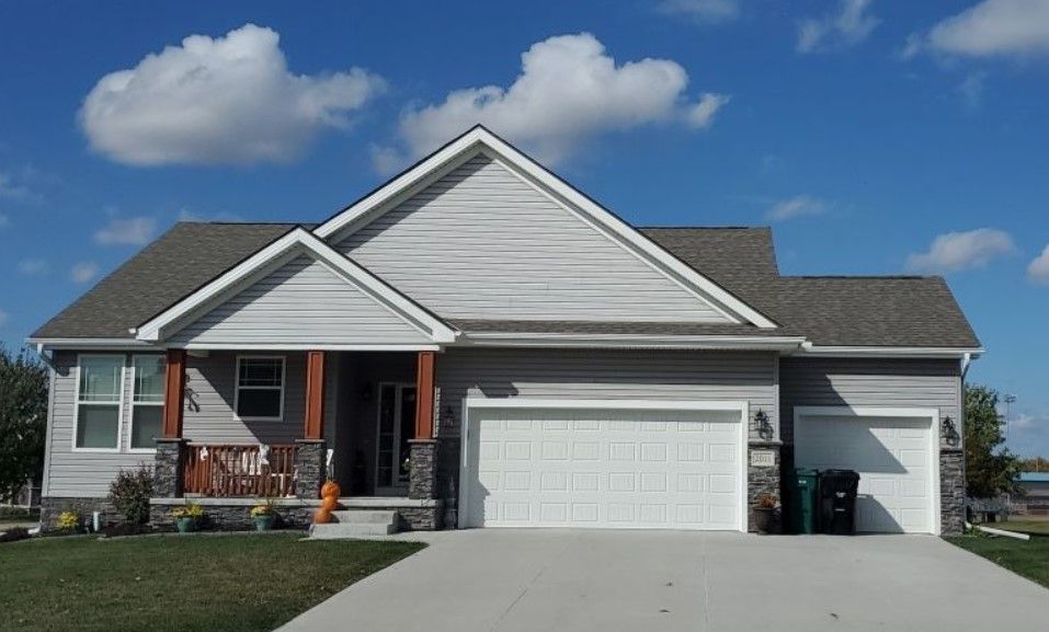 A house with two garage doors and a porch on a sunny day