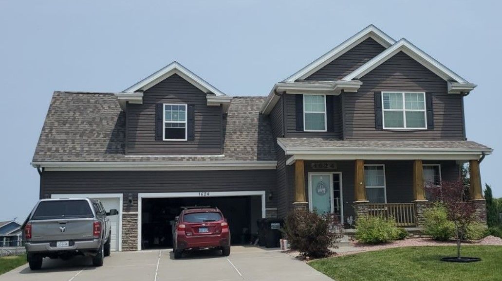 A large house with two cars parked in front of it.