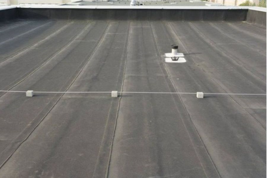 A black roof with a white pipe on it.