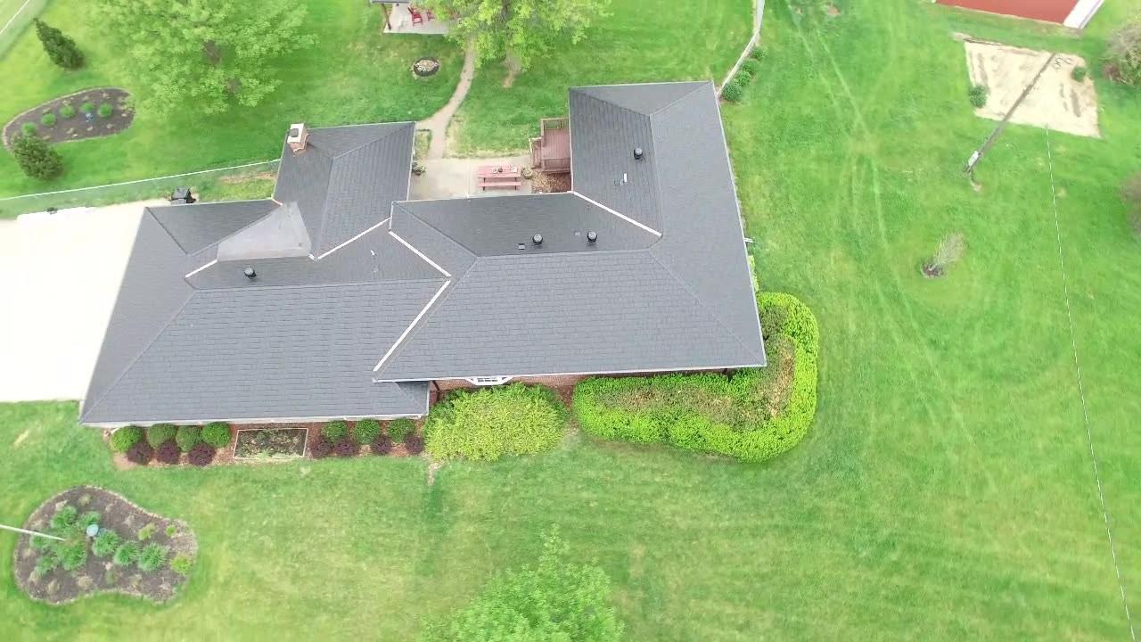 An aerial view of a house with a black roof and a large yard.