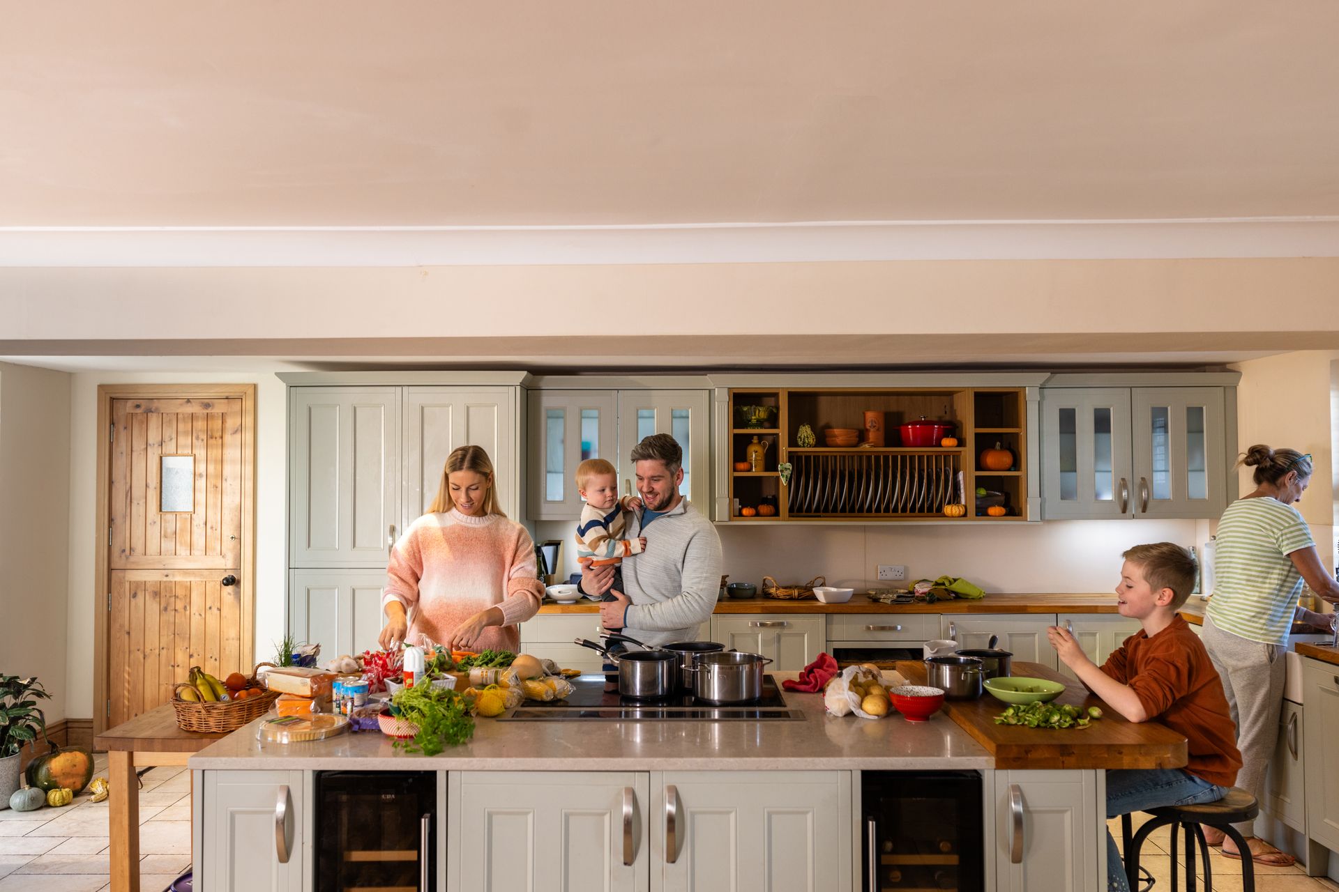 A family is standing in a kitchen preparing food.