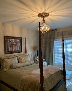 Bedroom with a four-poster bed, patterned bedding, and ornate ceiling light.