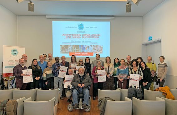 Foto grupal de personas con certificados en una sala de conferencias. Una pantalla muestra un póster.
