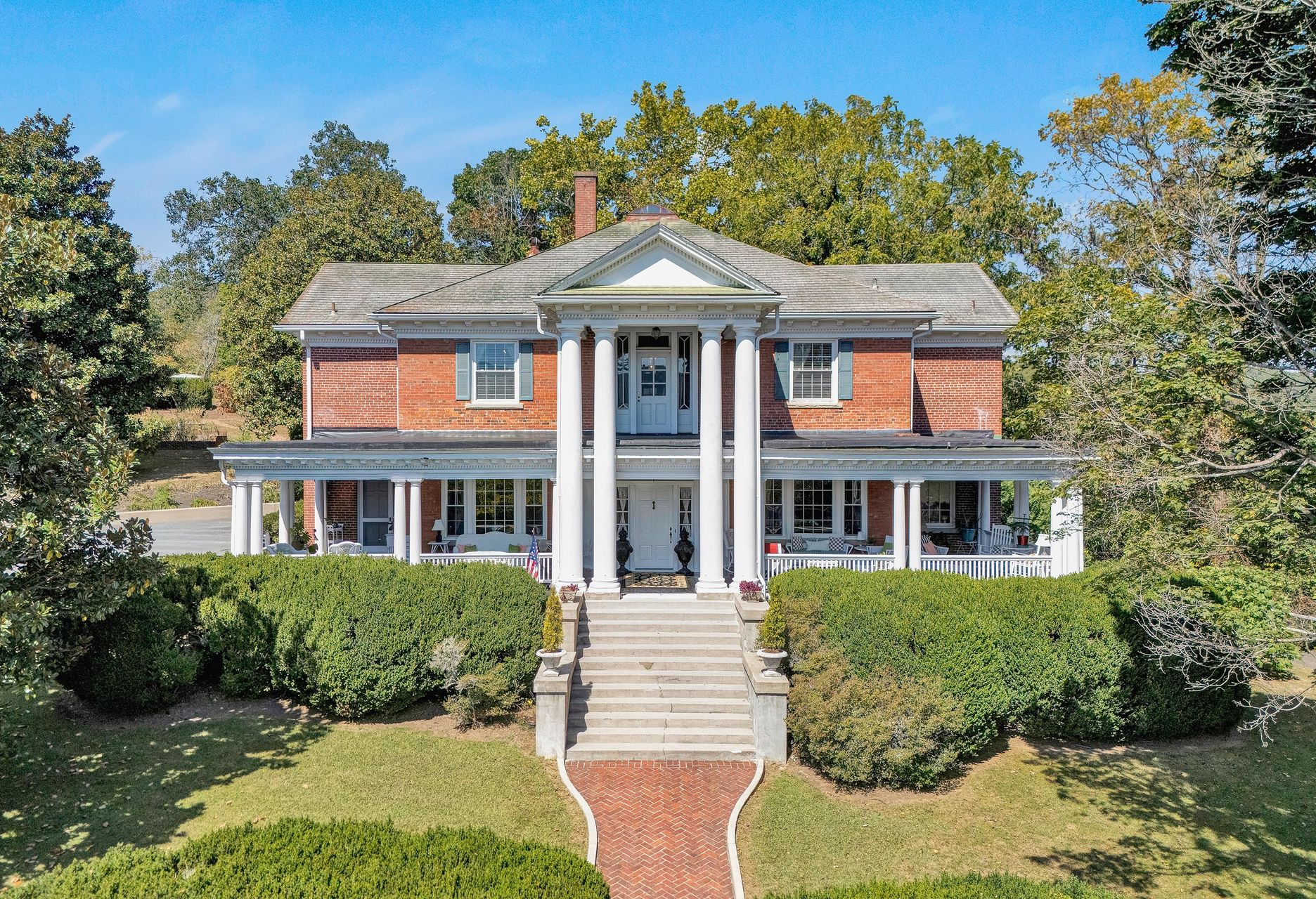 Brick colonial house with white columns, front steps, and a manicured lawn