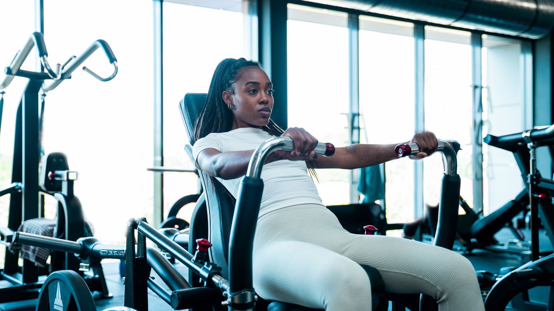Een vrouw zit op een machine in een sportschool.