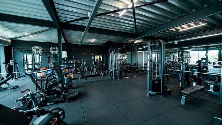 Een grote fitnessruimte vol met veel fitnessapparatuur.