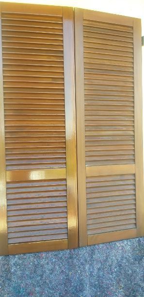 Porte armadio in legno a persiana, con telaio in ottone sopra un pannello murale blu goffrato.