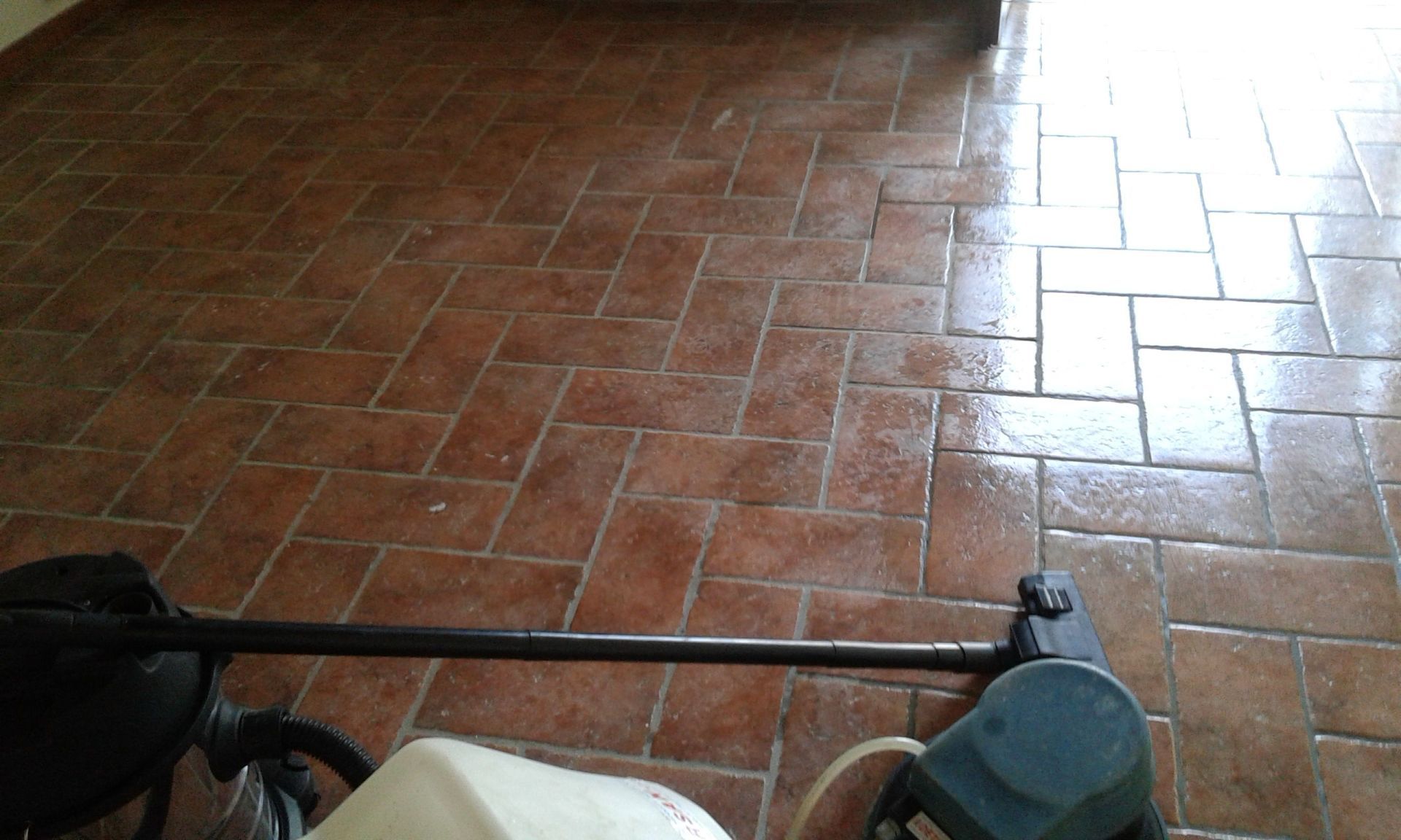 Manubrio e cestino anteriore di una bicicletta su un pavimento di piastrelle marrone rossiccio in una stanza soleggiata