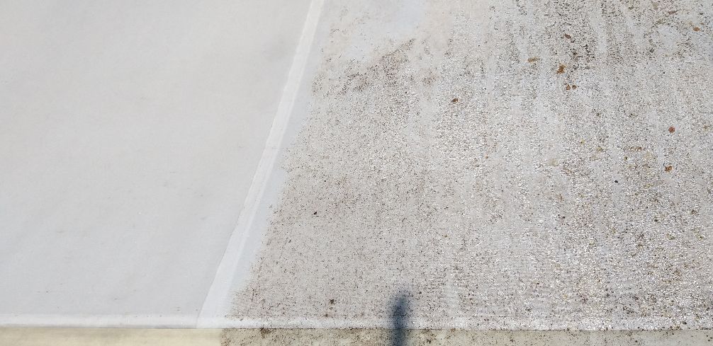 Parete bianca che incontra un pavimento macchiato e sporco in un angolo, con un’ombra scura alla base