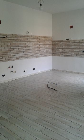 Cucina vuota in fase di ristrutturazione, con pavimento piastrellato e pareti del paraschizzi ancora da finire