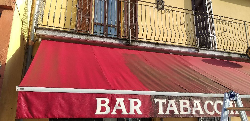 Tenda rossa con insegna bianca «BAR TABAC» sulla facciata di un edificio giallo