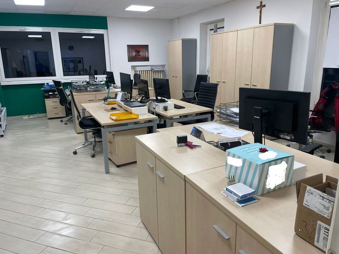 Ufficio con scrivanie, monitor, armadietti e una parete con finestre