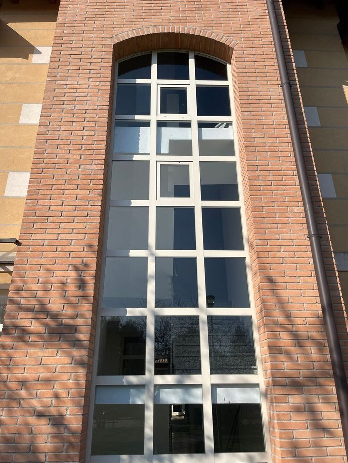 Alta finestra ad arco inserita nella facciata di un edificio in mattoni rossi.