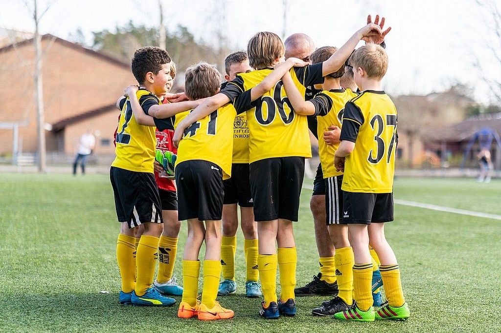 Barn i fotbollslag som peppar varandra.