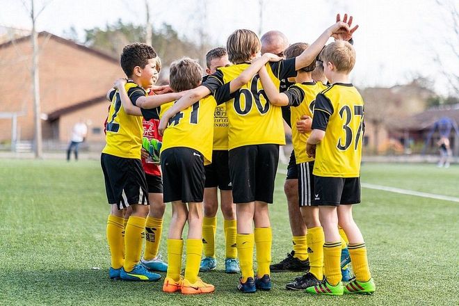 Killar i fotbollskläder håller varandra om axlarna.