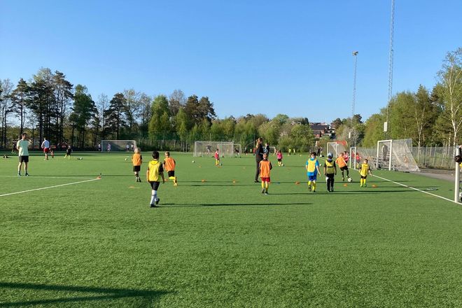 Barn spelar fotboll i solen.