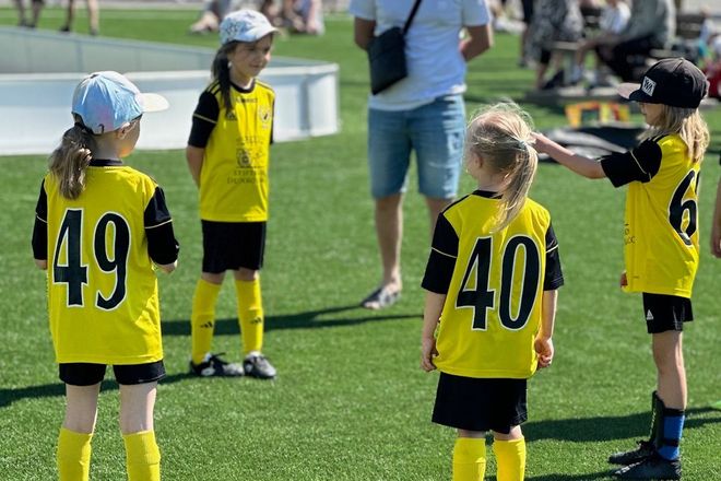 Flickor i fotbollskläder pratar på fotbollsplan.