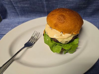 A hamburger is on a white plate with a fork