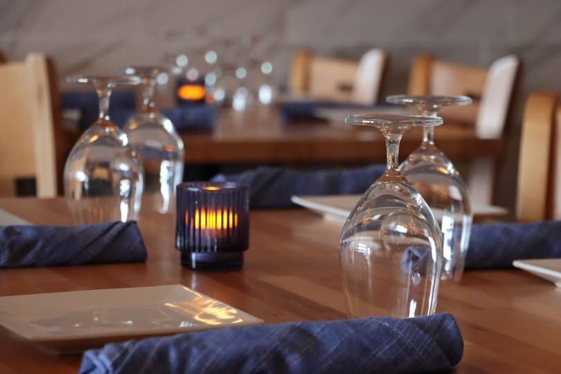 A restaurant table with wine glasses and a candle on it at Drift Seafood in Ventnor City, NJ