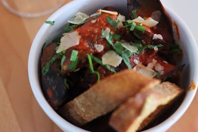 A bowl of mussels marinara and bread on a table