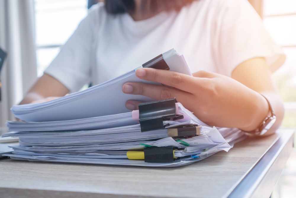Person holding and sorting through a stack of papers, office setting — Immigration Agents in Cairns North, QLD
