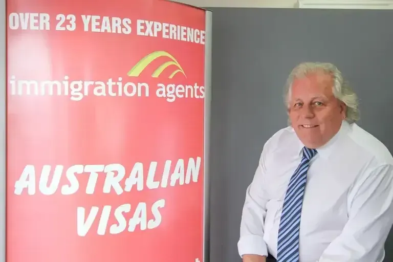 Man in White Shirt and Tie Stands Next to a Sign for Australian Visas — Immigration Agents in Cairns North, QLD