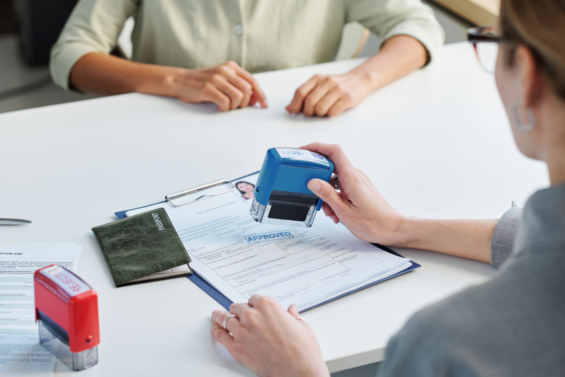 A Person Stamping a Document on a Desk, Near a Passport — Immigration Agents in Cairns North, QLD