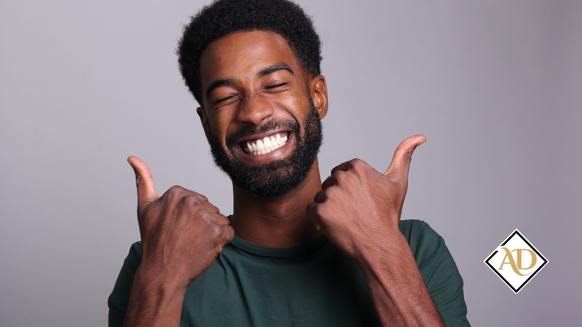 Smiling man giving double thumbs up against a gray background