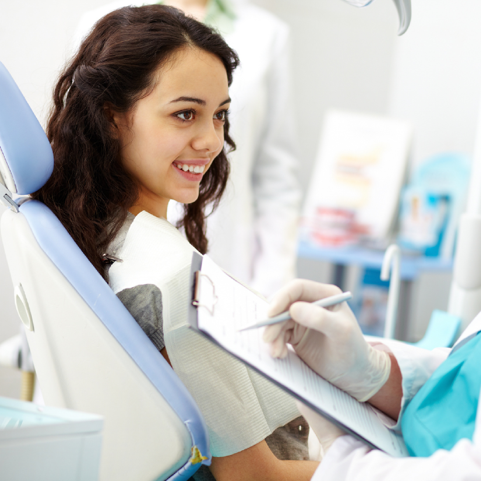 Dentist and assistant examining patient's teeth in a dental office.