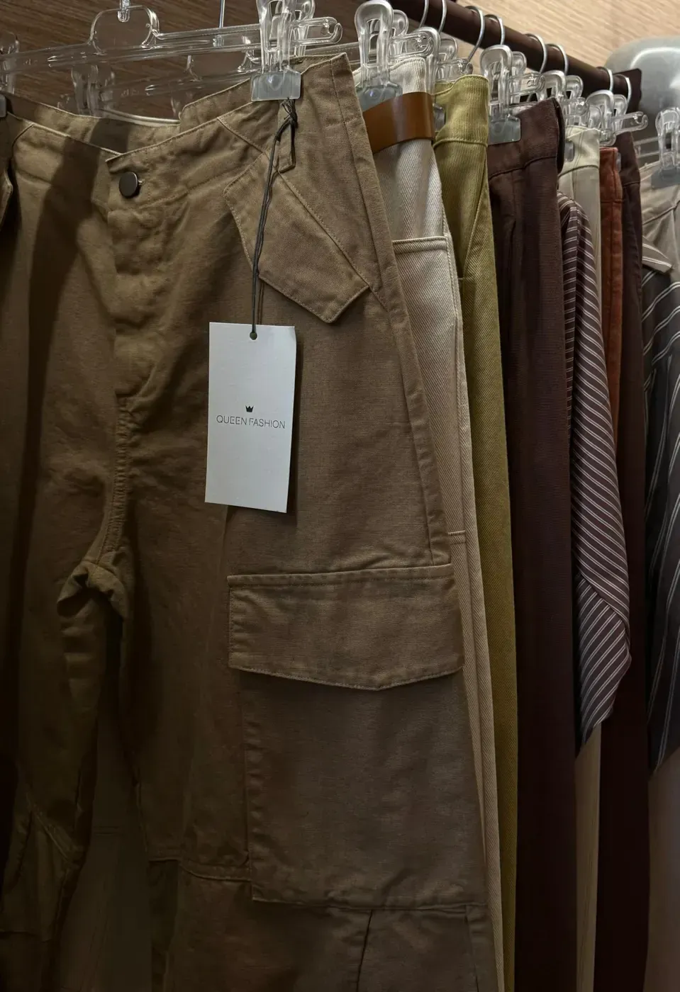 Pantaloni cargo color kaki appesi a uno scaffale, con l'etichetta attaccata.