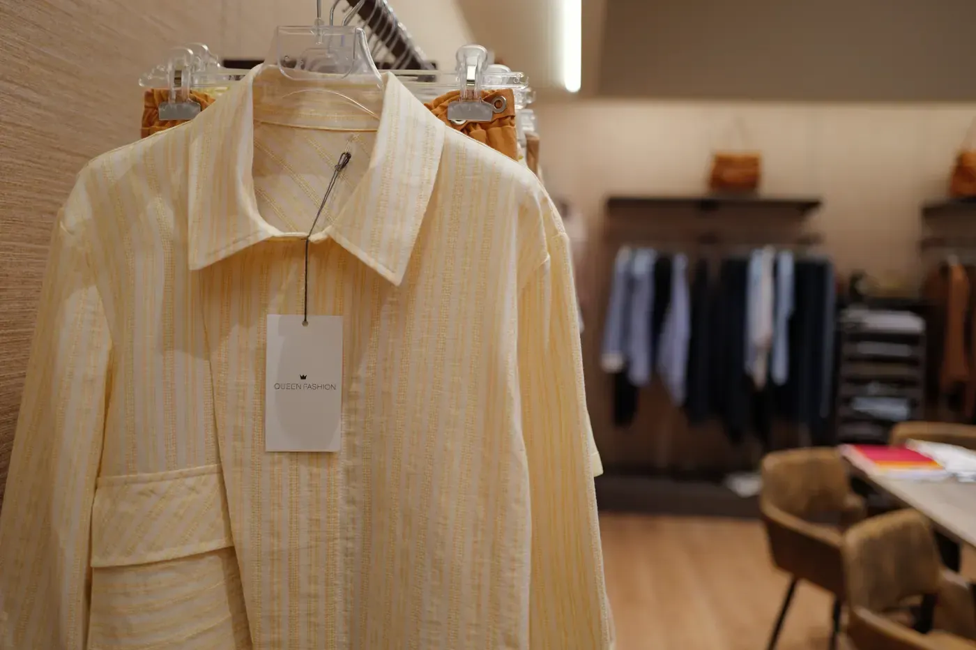 Camicia a righe color crema appesa a una gruccia all'interno di un negozio di abbigliamento.