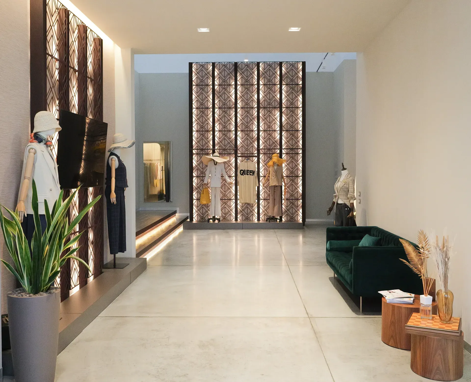 Corridoio moderno e minimalista di una boutique, con pannelli a parete decorati, pavimento lucido e sedute verdi.