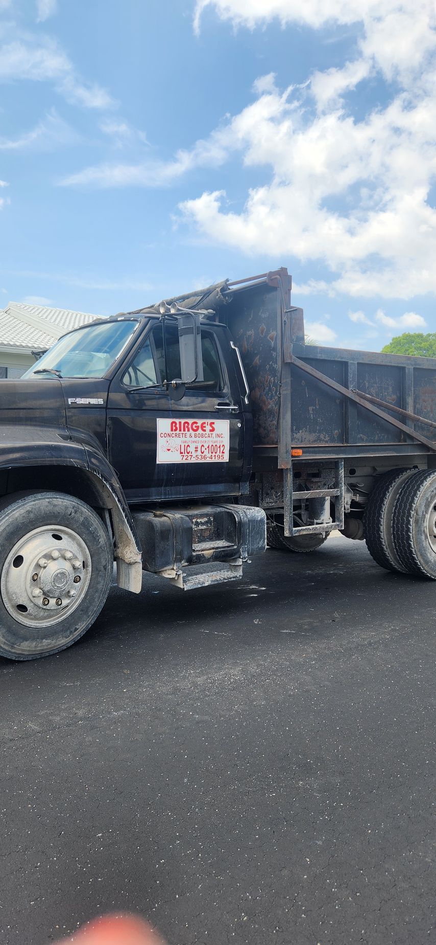 An orange dump truck is parked in front of a house.