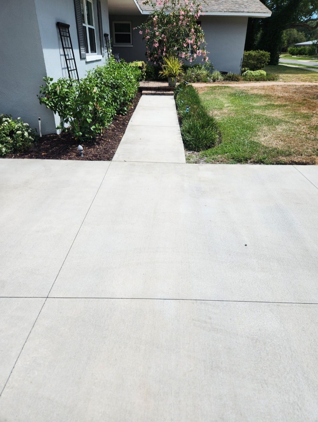 There is a concrete walkway leading to the front of a house.