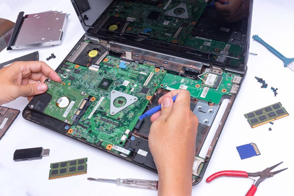 Person Disassembling Laptop, Surrounded by Components — Micromac Computers in Charmhaven, NSW